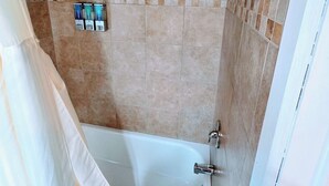 A bathroom with a bathtub, shower, and tiled walls.