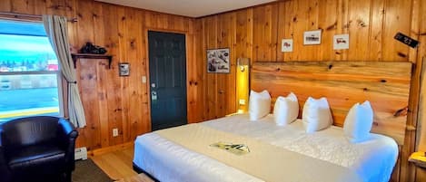 Ett hotellrum med en stor säng, en bänk, ett skrivbord och utsikt över omgivningarna.
