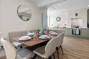 A modern dining area with a wooden table set for four, surrounded by upholstered chairs. - Comfortable Coastal Home near Meols Beach, perfect base with parking (Meols)