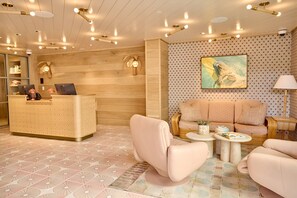 Un área de recepción con un mostrador de madera, asientos acolchados y un suelo estampado.