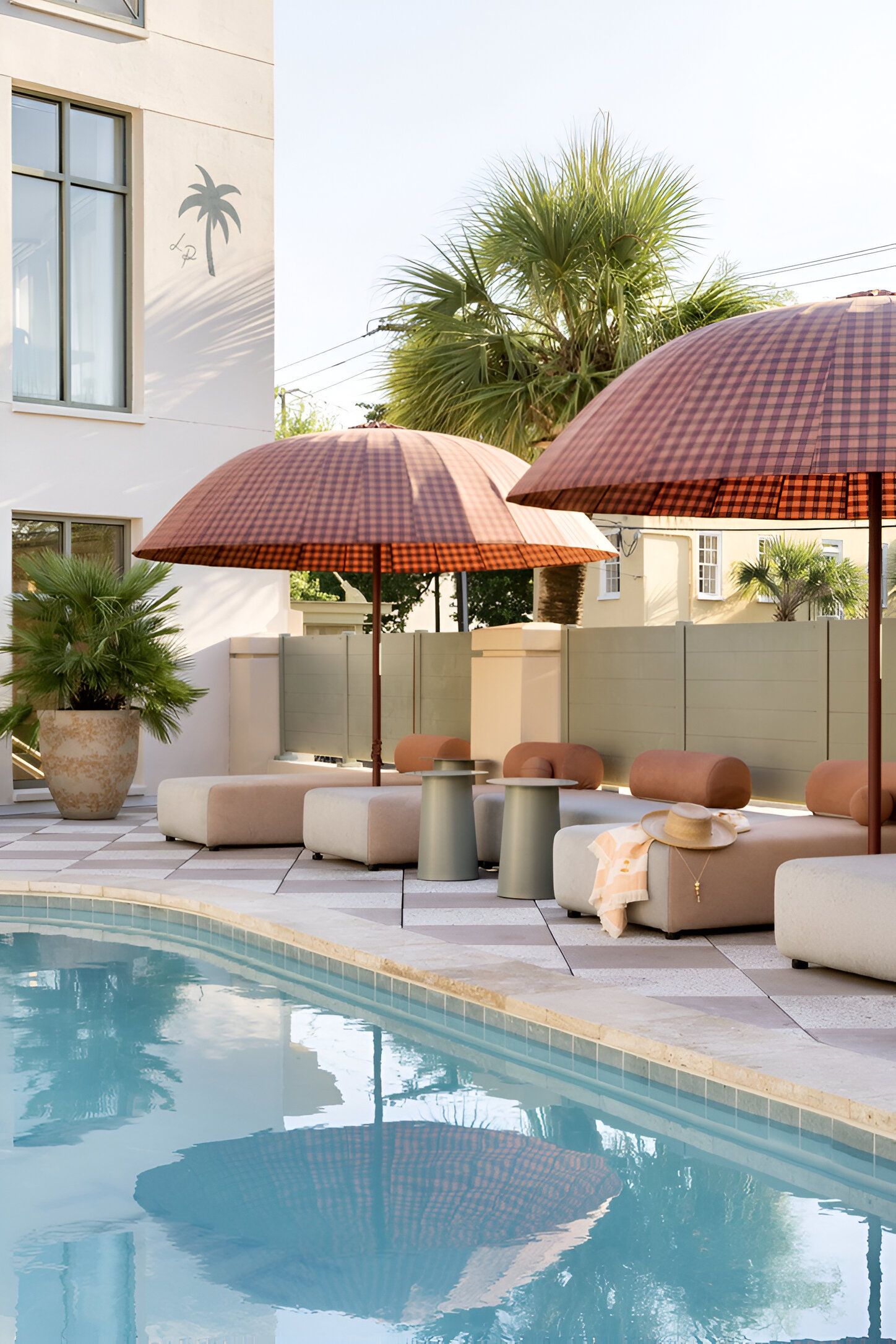 Un espace aménagé au bord de la piscine, avec des chaises longues, des parasols et un pot de fleurs.