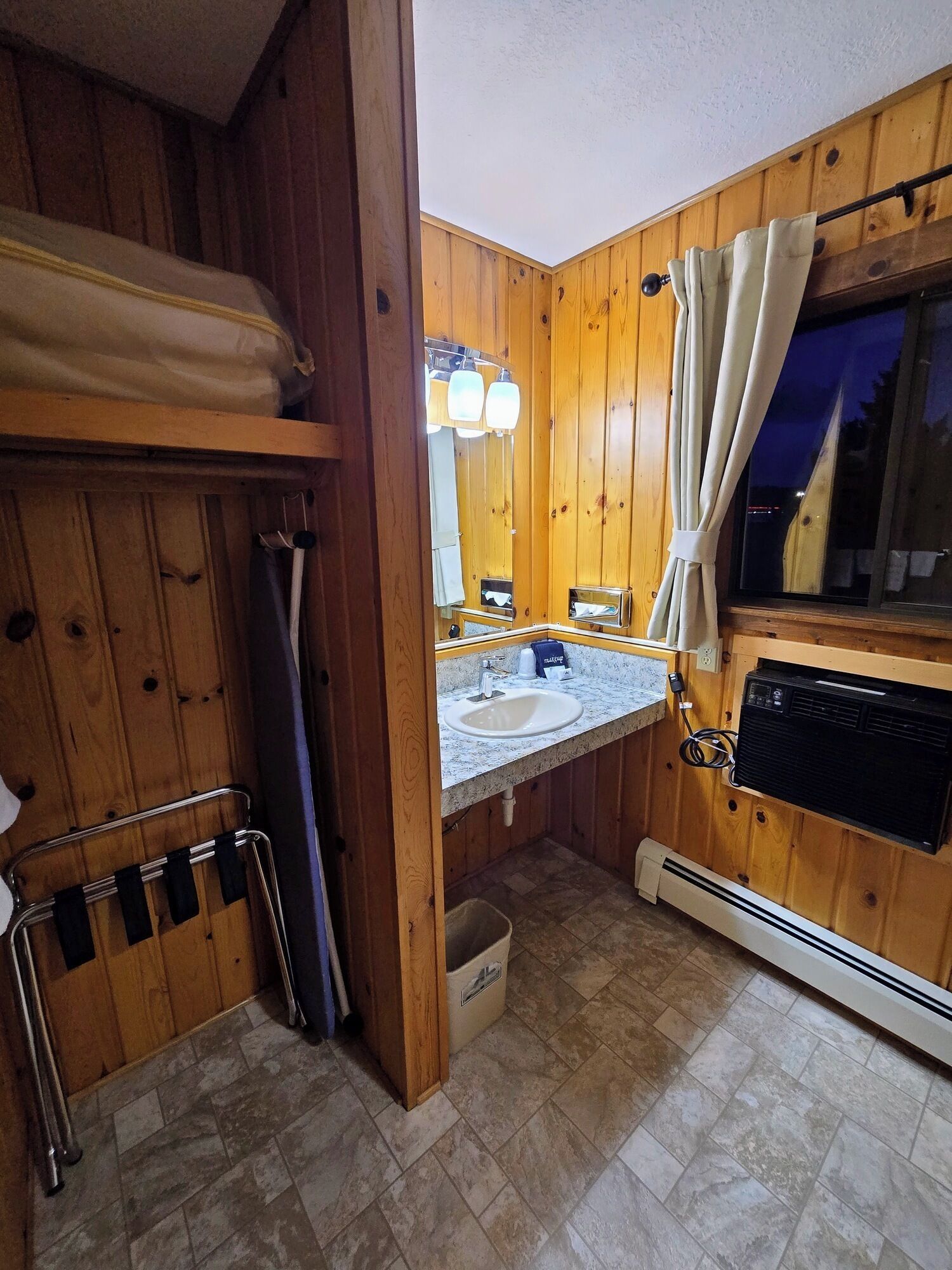 A wooden cabin bathroom with a sink, mirror, and heater.