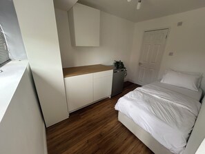 Ein Schlafzimmer mit einem Bett, einer kleinen Küchenzeile und einer weißen Tür.