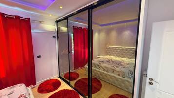A bedroom with a sliding glass door, a bed with a floral bedspread, and red circular rugs on the floor.