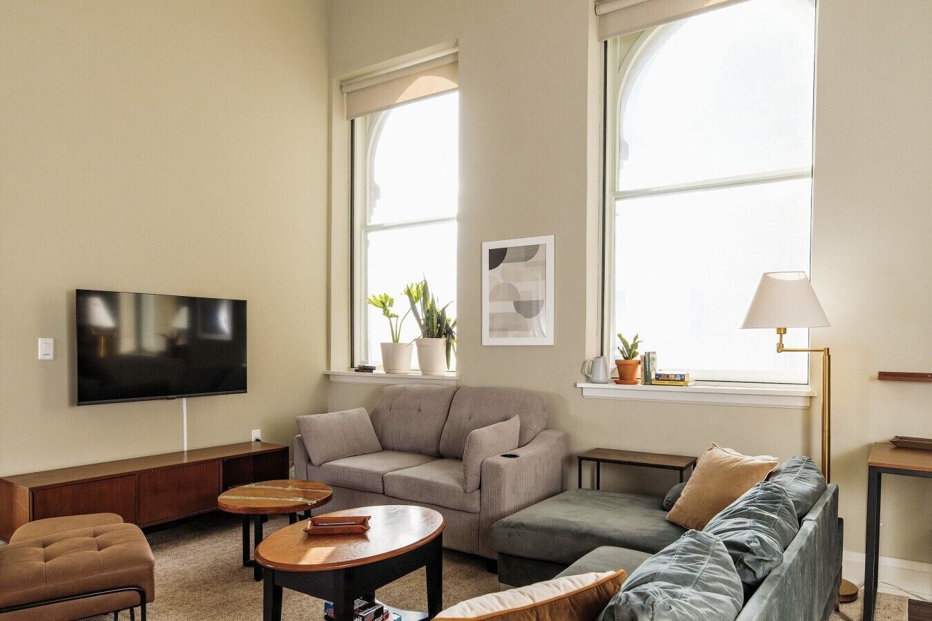 Una sala de estar con televisor de pantalla plana, dos sofás, una mesa de centro y una lámpara de pie.