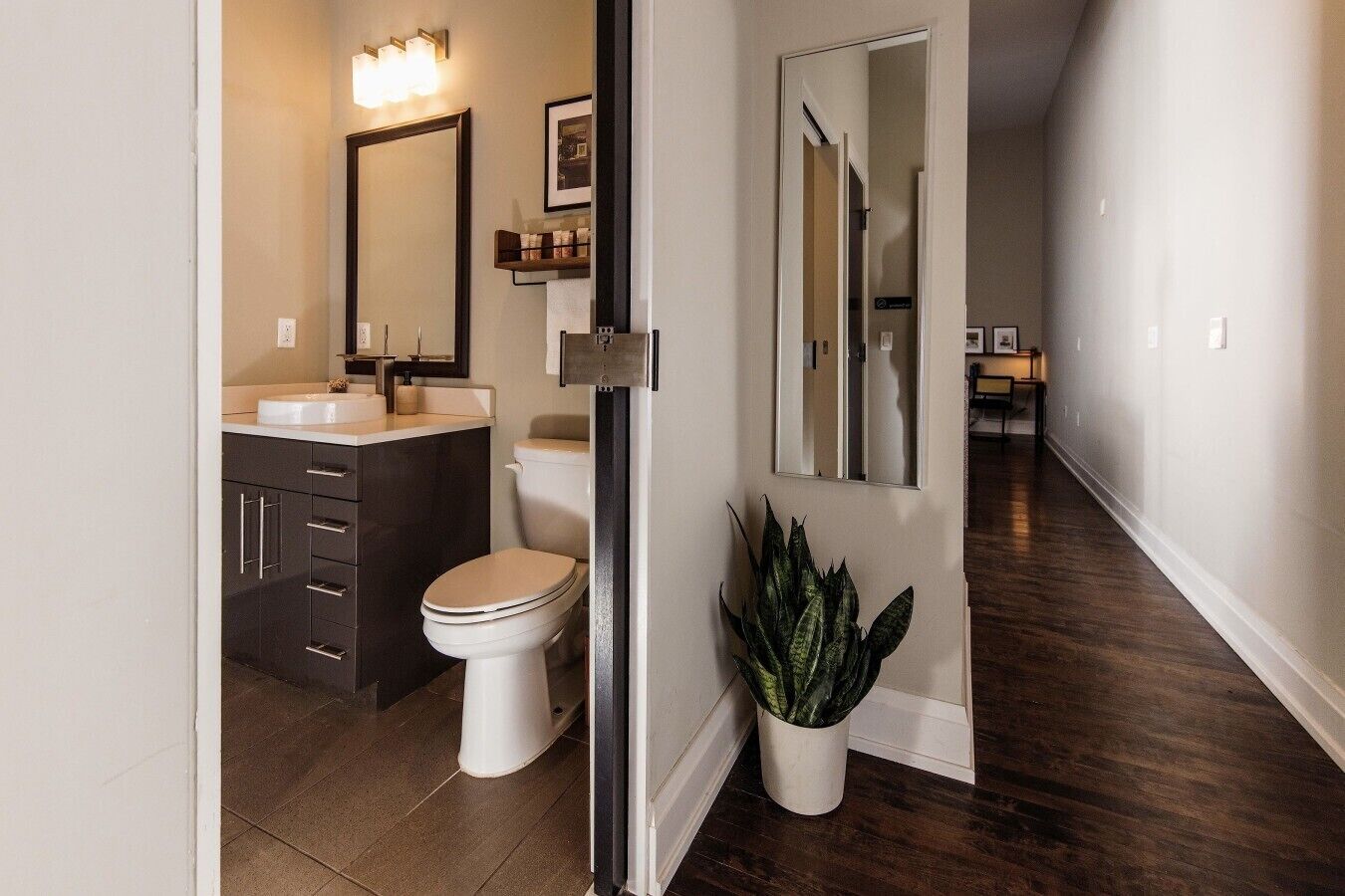 A modern bathroom with a toilet, sink, and dark cabinetry.