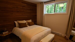 A wooden-paneled bedroom with a bed, bedside table, and a window with curtains. - Kozy KanataTremblant (261) (Amherst)