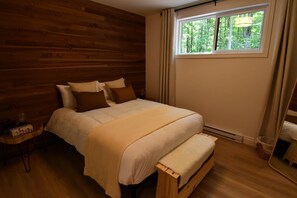 Ein Schlafzimmer mit Holzwänden, einem Bett, einem Nachttisch und einem Fenster mit Vorhängen.