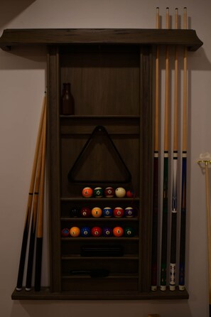 Ein Gestell aus Holz mit Billardstöcken und Billardkugeln.