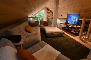 A cozy living room with a large sofa, ottoman, and a television on a wooden stand. - Kozy KanataTremblant (261) (Amherst)