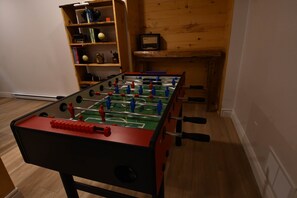 Ein Fußballtisch in einem Raum mit Holzboden und einem Bücherregal im Hintergrund.