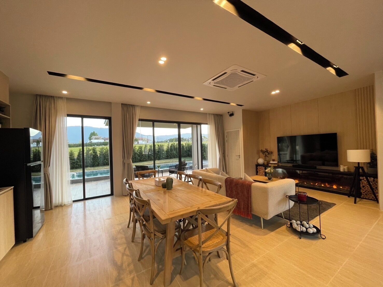 A modern living room with a dining area, a flat-screen TV, and a fireplace.