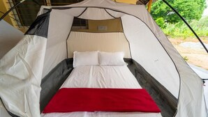 A tent with a bed, a window, and a red blanket.