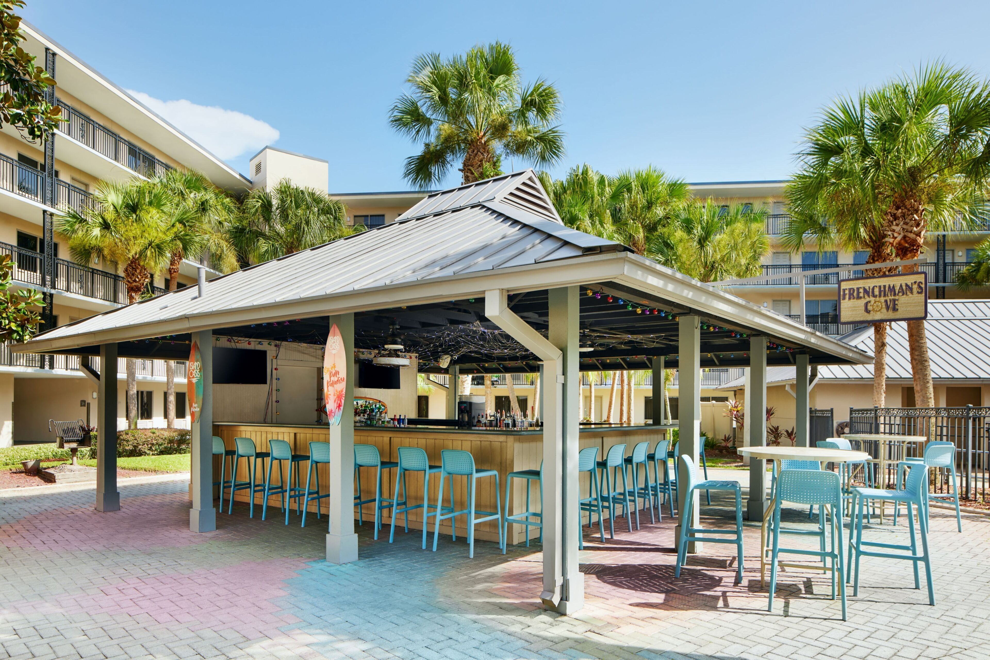A covered outdoor bar area with multiple seating arrangements, including bar stools and tables.