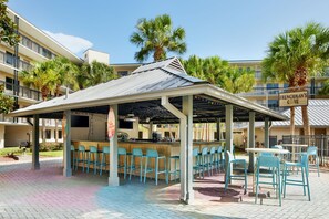 A covered outdoor bar area with multiple seating arrangements, including bar stools and tables. - ADA Suite w/ Tub | Nr Disney | Breakfast Included (Kissimmee)