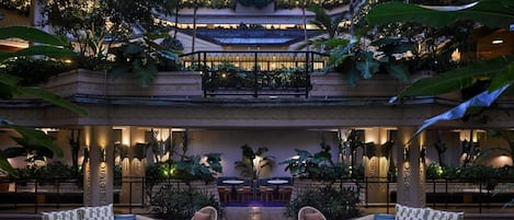 A multi-level outdoor lounge area with seating arrangements, a pool, and lush greenery.