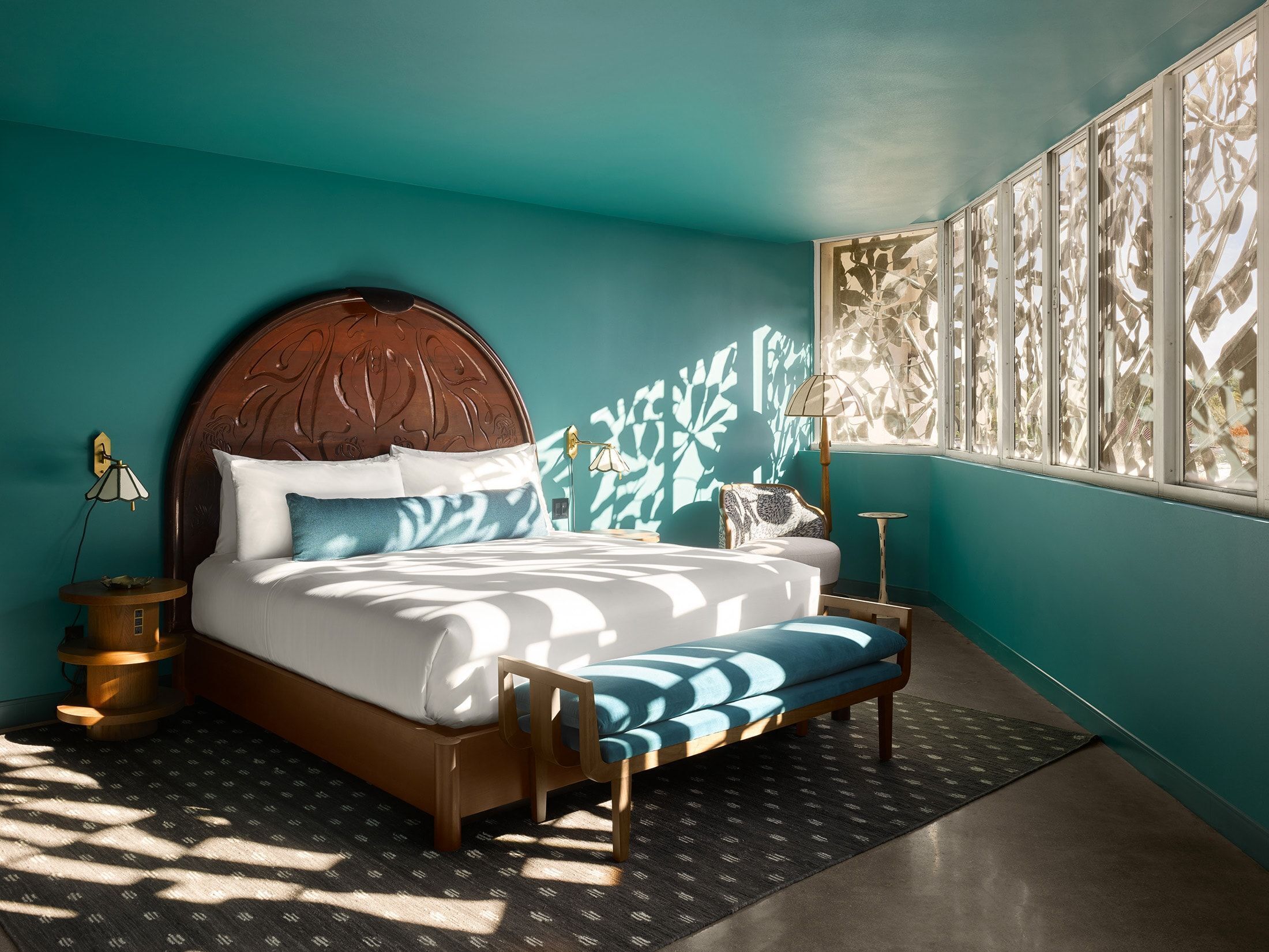 Een moderne slaapkamer met een groot bed, een houten hoofdbord en uitzicht op het omliggende landschap door een raam met decoratieve decoratie.