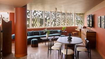A modern interior with a sofa, dining table, chairs, and a piano.
