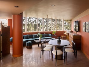 Un interior moderno con un sofá, una mesa de comedor, sillas y un piano.