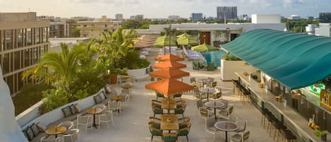 Une terrasse sur le toit avec des espaces de détente en plein air, une piscine et un bar.