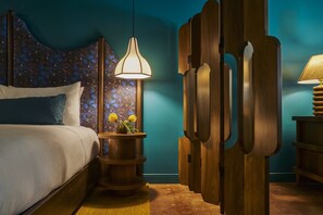 A bedroom with a bed, a nightstand, a wall-mounted lamp, and a decorative wooden panel.