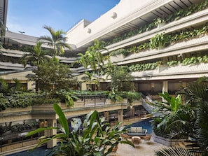 A multi-level hotel atrium with a central pool, surrounded by lush greenery and multiple balconies. - Accessible Double King w/ Balcony + Breakfast (Miami)