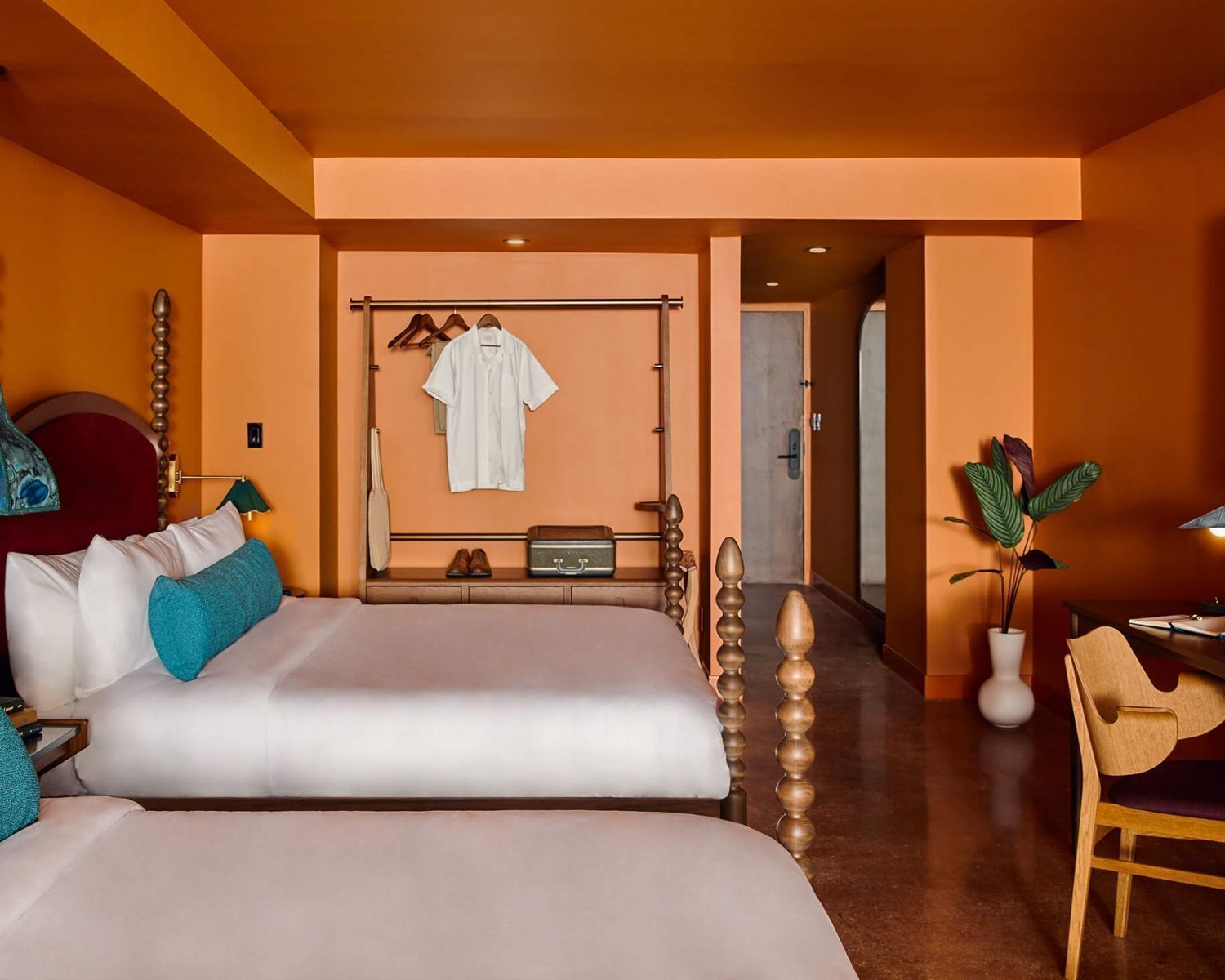 A hotel room with two beds, a wardrobe, a desk, and a chair.