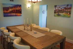Ein Esszimmer mit einem Holztisch, weißen Stühlen und drei Bildern an den Wänden.