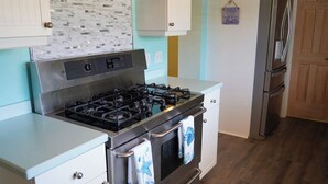 A kitchen with a stainless steel stove, white cabinets, and a wooden floor. - Large Waterfront Retreat with Deep Water Dock! (St Augustine)