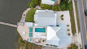 A large building with a swimming pool, surrounded by greenery and a road. - Large Waterfront Retreat with Deep Water Dock! (St Augustine)