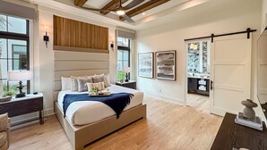 Ein geräumiges Schlafzimmer mit einem großen Bett, Holzbalkendecke, Deckenventilator und Blick ins Freie durch ein Fenster.