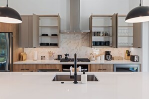 A modern kitchen with a central island, double overhead cabinets, and a built-in stove. - Dallas Retreat, Mins to DT, Hot Tub & Big Backyard (Dallas)