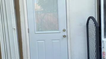 A white door with a glass panel, a metal gate, and a small step leading to the door.