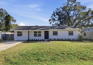 A single-story house with a front porch, a small front yard, and a tree to the right. - Modern 4BR Retreat | Near Lakeland and Legoland (Auburndale)