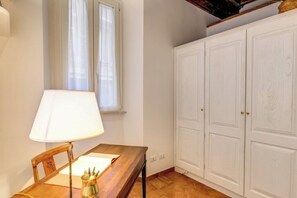 Ein Zimmer mit einem Holztisch, einer Lampe und einem weißen Kleiderschrank.