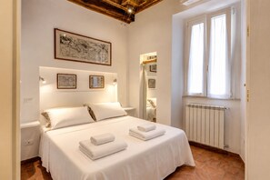 A hotel room with a bed, a window, and wall-mounted artwork. - Charming Roman Home Just Steps from Campo de' Fiori (Roma)