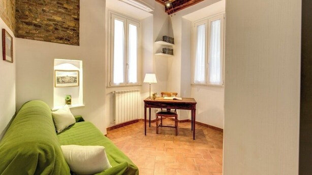 Ein Zimmer mit einem grünen Sofa, einem Holztisch und einem Fenster mit Blick.