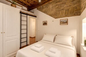 Une chambre à coucher avec un lit, deux oreillers, une armoire blanche, une porte coulissante et un plafond en briques.