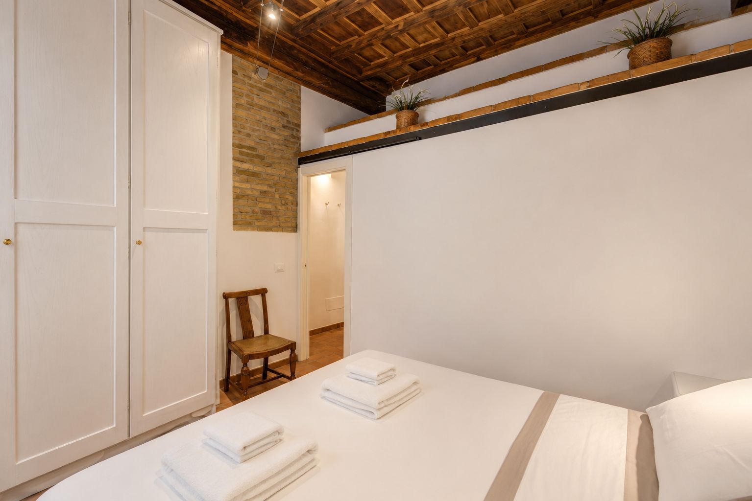 A bedroom with a bed, a chair, and a wardrobe.