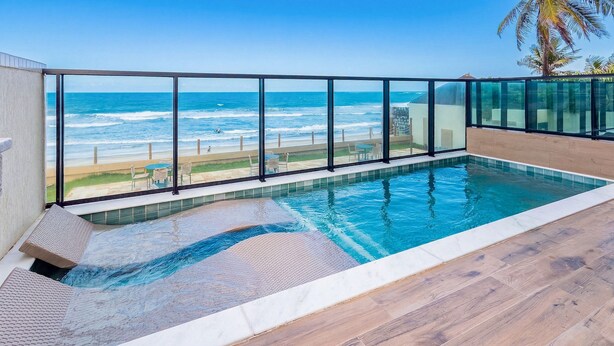 A swimming pool with a view of the ocean and beach. - Vila Porto by Carpediem In Front of Porto de Galinhas Beach (Ipojuca)