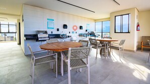 A modern office space with a dining area, a kitchenette, and a view through large windows. - Vila Porto by Carpediem In Front of Porto de Galinhas Beach (Ipojuca)