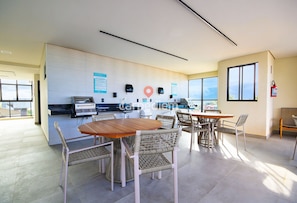 A modern office space with a dining area, a kitchenette, and a view through large windows. - Vila Porto by Carpediem In Front of Porto de Galinhas Beach (Ipojuca)