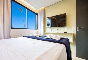 A hotel room with a bed, a TV, a mirror, and a window with curtains. - Vila Porto by Carpediem In Front of Porto de Galinhas Beach (Ipojuca)