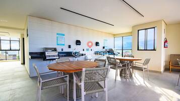 Um espaço de escritório moderno com área de refeições, kitchenette e vista através de grandes janelas.