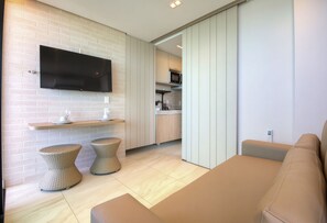 A modern living room with a flat-screen TV mounted on a brick wall, a sofa, and two wicker side tables. - Vila Porto by Carpediem In Front of Porto de Galinhas Beach (Ipojuca)