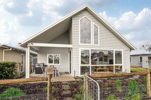 Ein Wohnhaus mit überdachter Terrasse, Grillplatz und großem Fenster mit Blick auf den Garten.