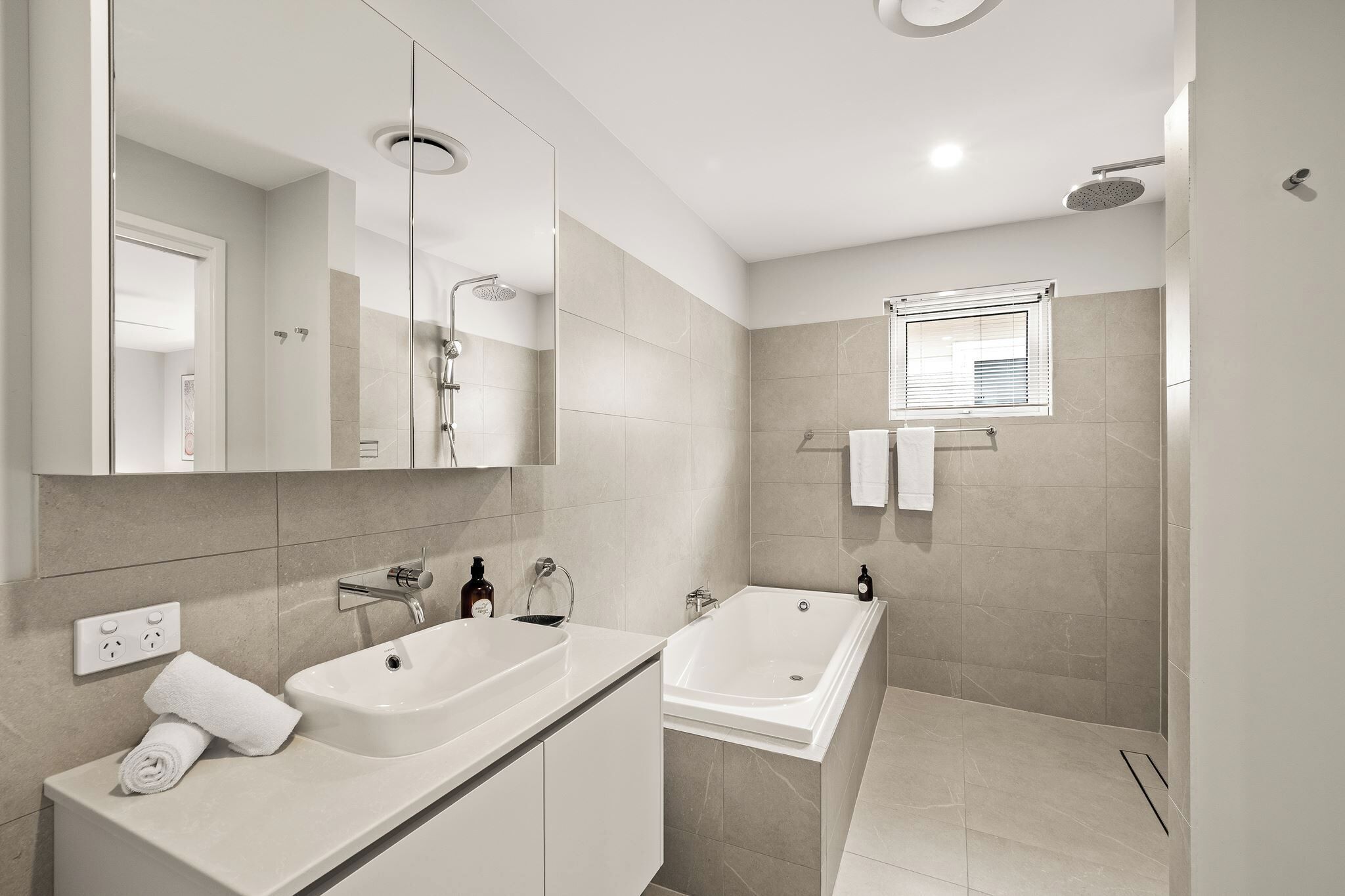 Ein modernes Badezimmer mit zwei Waschbecken, einer Dusche und einem großen Spiegel.