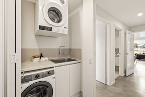 Ein kleiner Waschraum mit Waschmaschine, Waschbecken und einer Trockenständer.