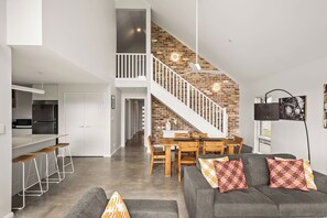 Ein modernes Interieur mit einer Küche, einem Essbereich und einer Treppe an einer Ziegelwand.