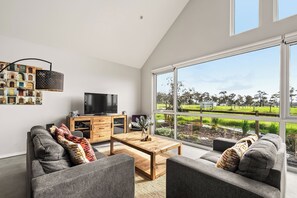 Una sala de estar moderna con un ventanal grande, un televisor de pantalla plana y una mesa de centro de madera.